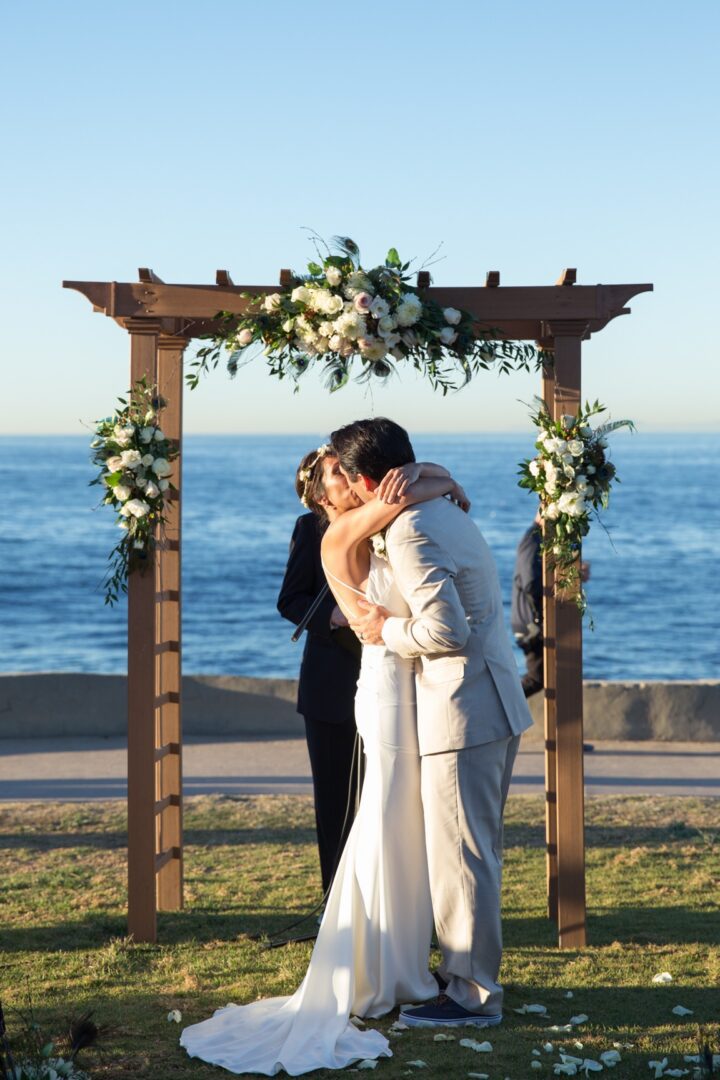 Bride and groom kissing at oceanfront altar.