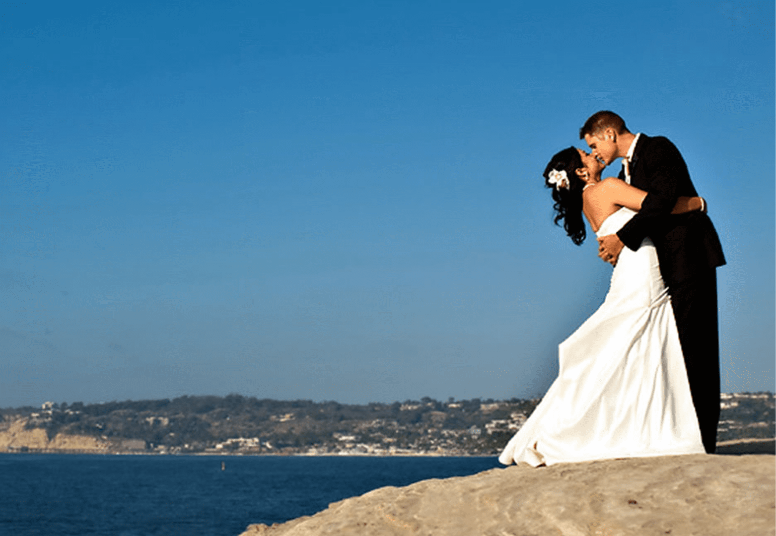 Newlyweds embrace with scenic ocean backdrop
