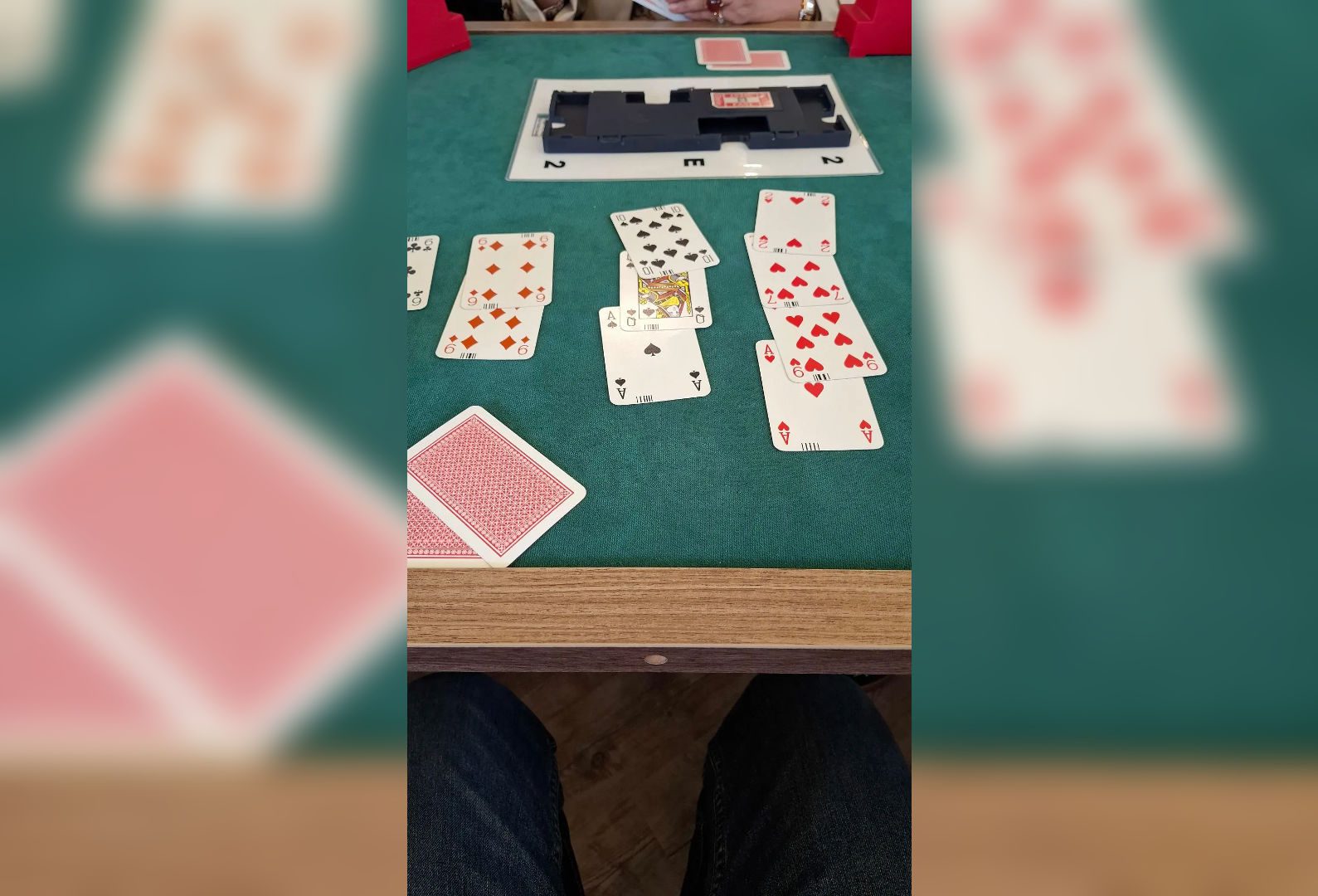 A poker game in progress with cards and poker chips on a green felt table.
