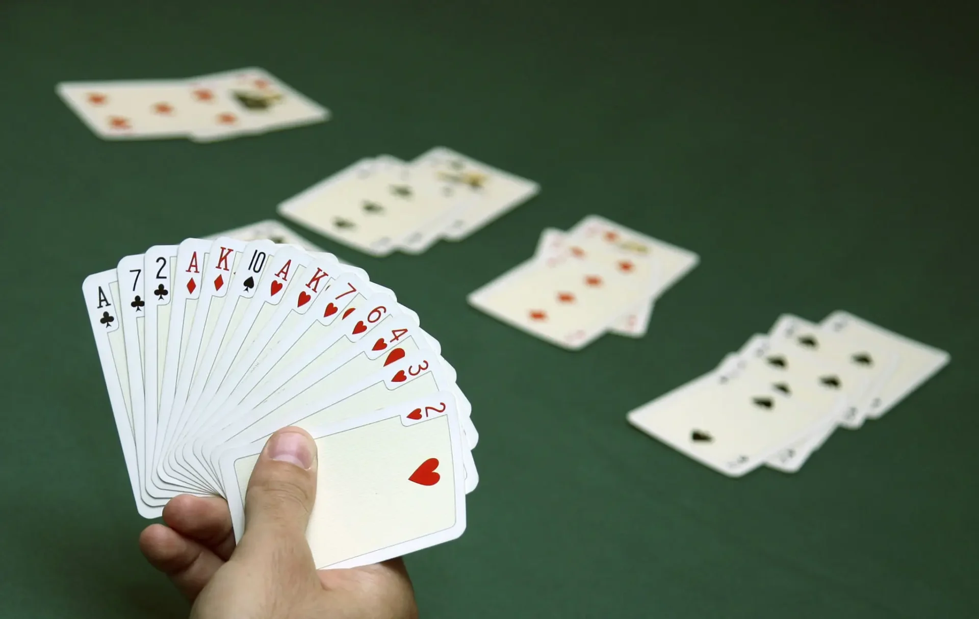A hand holding a full suit of hearts cards in a card game.